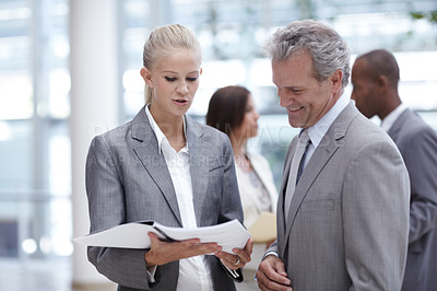 Buy stock photo A pretty businesswoman presenting a binder to an impressed senior executive