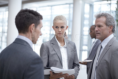 Buy stock photo A diverse group of serious-looking businesspeople looking over paperwork together