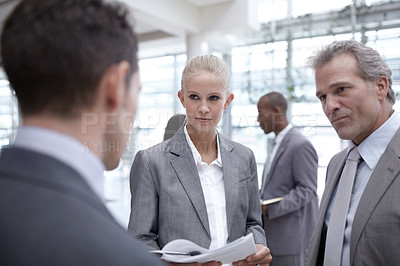 Buy stock photo A diverse group of serious-looking businesspeople looking over reports together