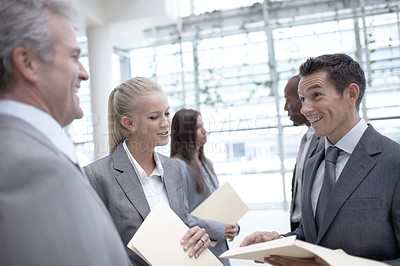 Buy stock photo A diverse group of happy-looking executives talking about a report together