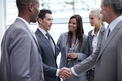 Buy stock photo A diverse group of businesspeople looking on as a coworker and their boss shake hands