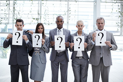 Buy stock photo Concept shot of a diverse group of business executives holding up placards with question marks on them