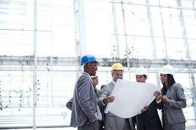 Buy stock photo A diverse group of architects looking over blueprints together with copyspace