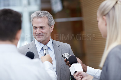 Buy stock photo Shot of a mature businessman being interviewed by reporters