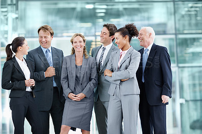 Buy stock photo Positive group of businesspeople standing together and smiling while surrounding a coworker - portrait 