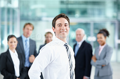Buy stock photo Attractive young business associate smiling with his colleagues in the background - portrait 