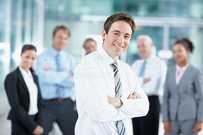 Buy stock photo Attractive young business associate smiling with his coworkers in the background - portrait 