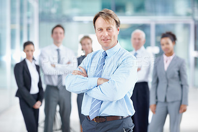 Buy stock photo Confident mature business executive smiling while standing with his team behind him - portrait 