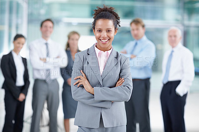 Buy stock photo Smiling young African businesswoman standing with her coworkers behind her - portrait 