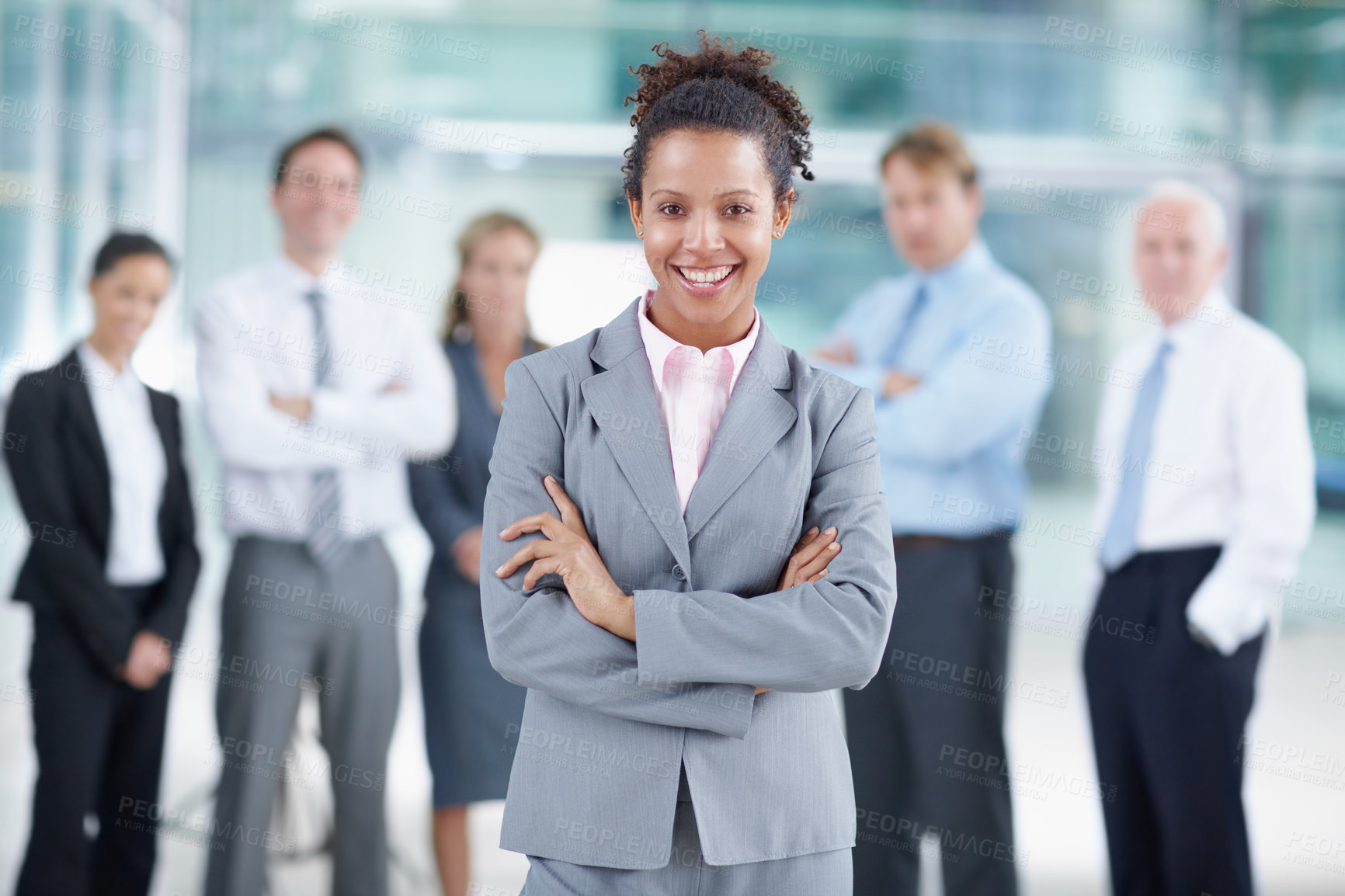 Buy stock photo Smiling young African businesswoman standing with her coworkers behind her - portrait 