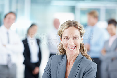 Buy stock photo Laughing mature businesswoman with her business team behind her - portrait 