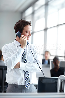 Buy stock photo Young businessman standing in the office while on the phone 