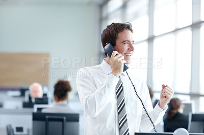 Buy stock photo Young businessman standing in the office while on the phone and looking positive