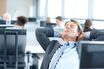 Buy stock photo Mature businessman sitting at a computer in the office and stretching 