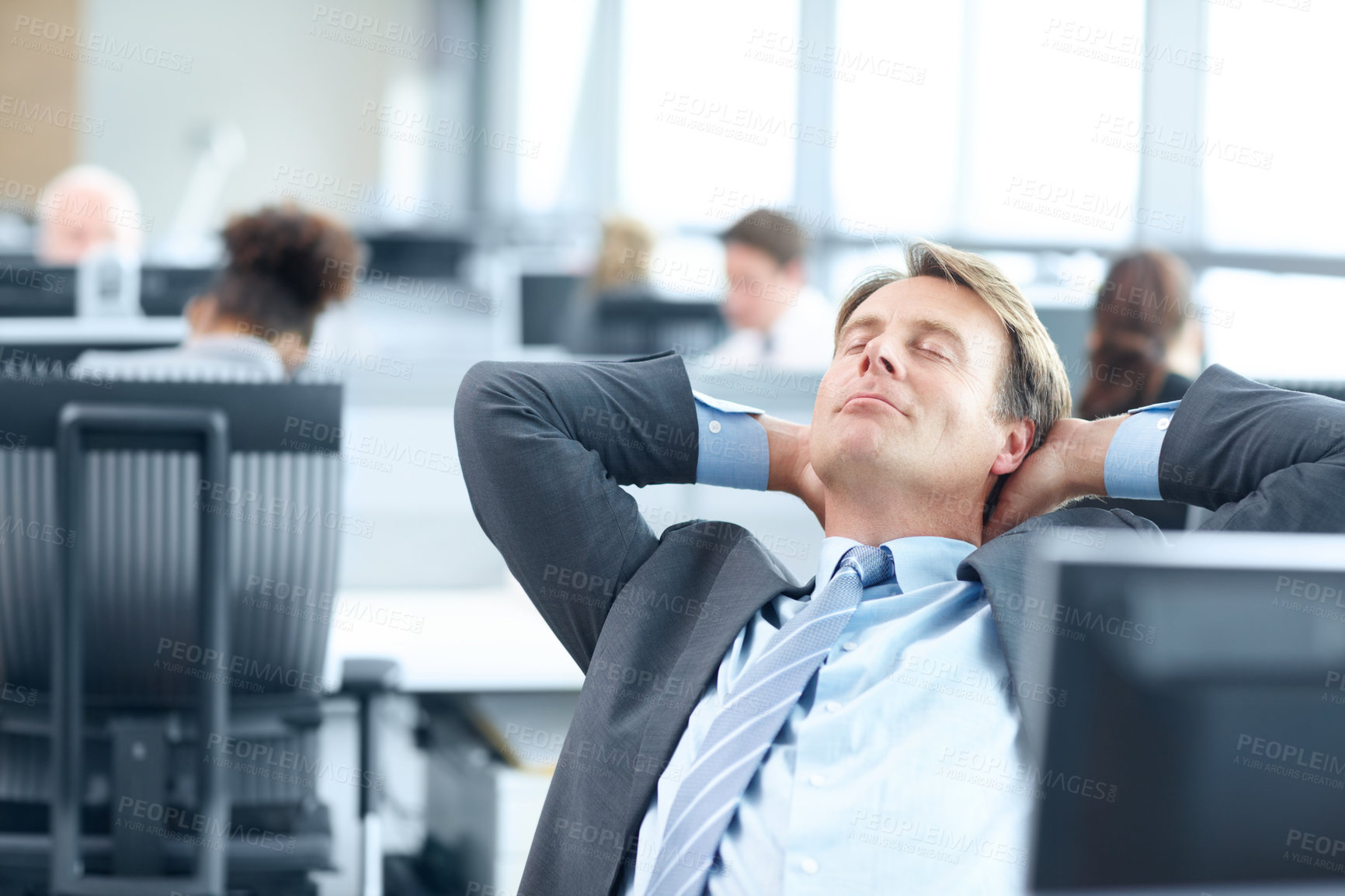 Buy stock photo Mature businessman sitting at a computer in the office and stretching 