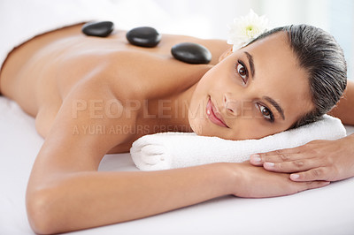 Buy stock photo Smile, hot stone and portrait of woman with massage at spa for wellness, health and back treatment. Self care, cosmetic and young female person relaxing for warm rock therapy at natural beauty salon.