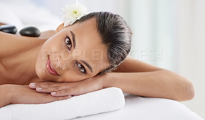 Buy stock photo Portrait, hot stone and woman laying for massage at spa for wellness, health and back treatment. Self care, cosmetic and young female person relaxing for warm rock therapy at natural beauty salon.