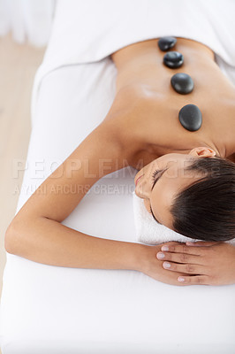 Buy stock photo Woman, spa and hot stone for wellness, luxury and satisfaction with skin, salon. Lady, self care and therapy for stress relief, zen and peace on massage table with beauty and health or wellbeing