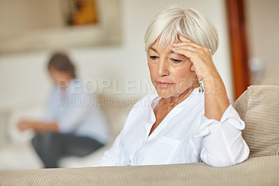 Buy stock photo Shot of a senior woman looking sad while sitting on the sofa at home