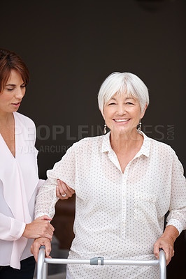 Buy stock photo Shot of a woman assisting her elderly mother who's using a walker for support