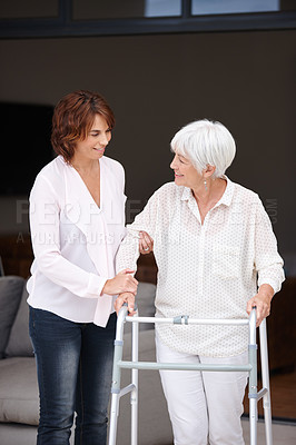 Buy stock photo Shot of a woman assisting her elderly mother who's using a walker for support