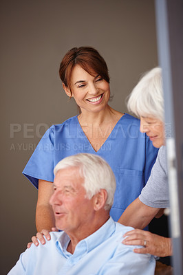Buy stock photo Cropped shot of a female nurse standing by her senior patient and his wife