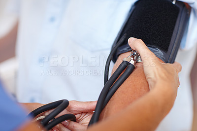 Buy stock photo Cropped shot of a healthcare worker checking a patient's blood pressure