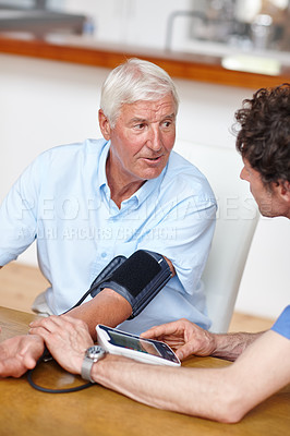 Buy stock photo Shot of a doctor checking a senior patient's blood pressure