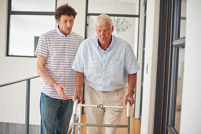 Buy stock photo Shot of a man assisting his elderly father with an orthopedic walker