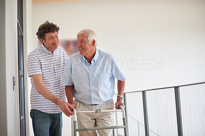 Buy stock photo Shot of a man assisting his elderly father with an orthopedic walker