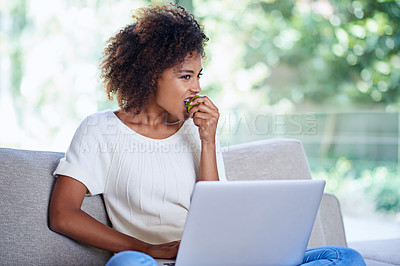 Buy stock photo Laptop, apple and African woman eating, sofa and afro while at home lounge for relax. Technology, computer or scrolling on social media website, app or internet for connection and with healthy snack
