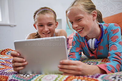 Buy stock photo Shot of two teenage friends using a digital tablet together at home