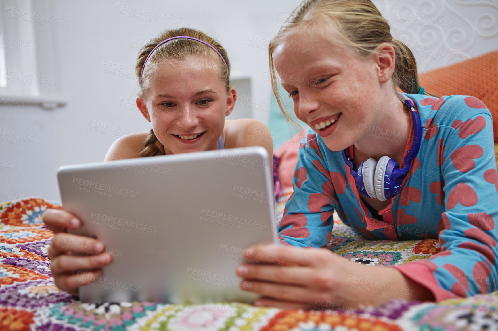 Buy stock photo Shot of two teenage friends using a digital tablet together at home