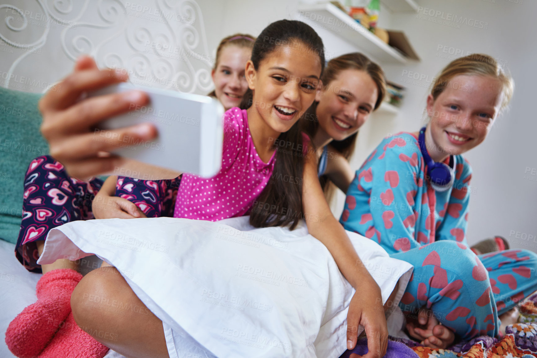 Buy stock photo Shot of a group of teenage friends taking a selfie together during a sleepover