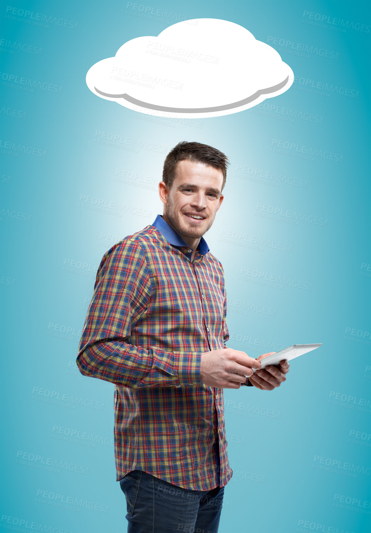 Buy stock photo Portrait of a young man standing and holding a digital tablet against a blue background with a cloud graphic above him