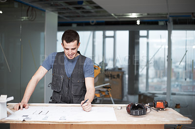 Buy stock photo Young architect working on his plans while at a construction site