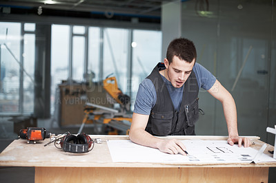 Buy stock photo Young architect working on his plans while at a construction site