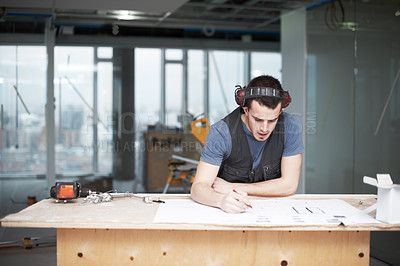 Buy stock photo Young architect working on his plans while at a construction site