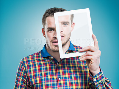 Buy stock photo A young man holding an advanced digital tablet in front of his face