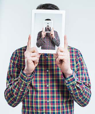 Buy stock photo Surreal shot of a young man holding an advanced digital tablet in front of his face, duplicated