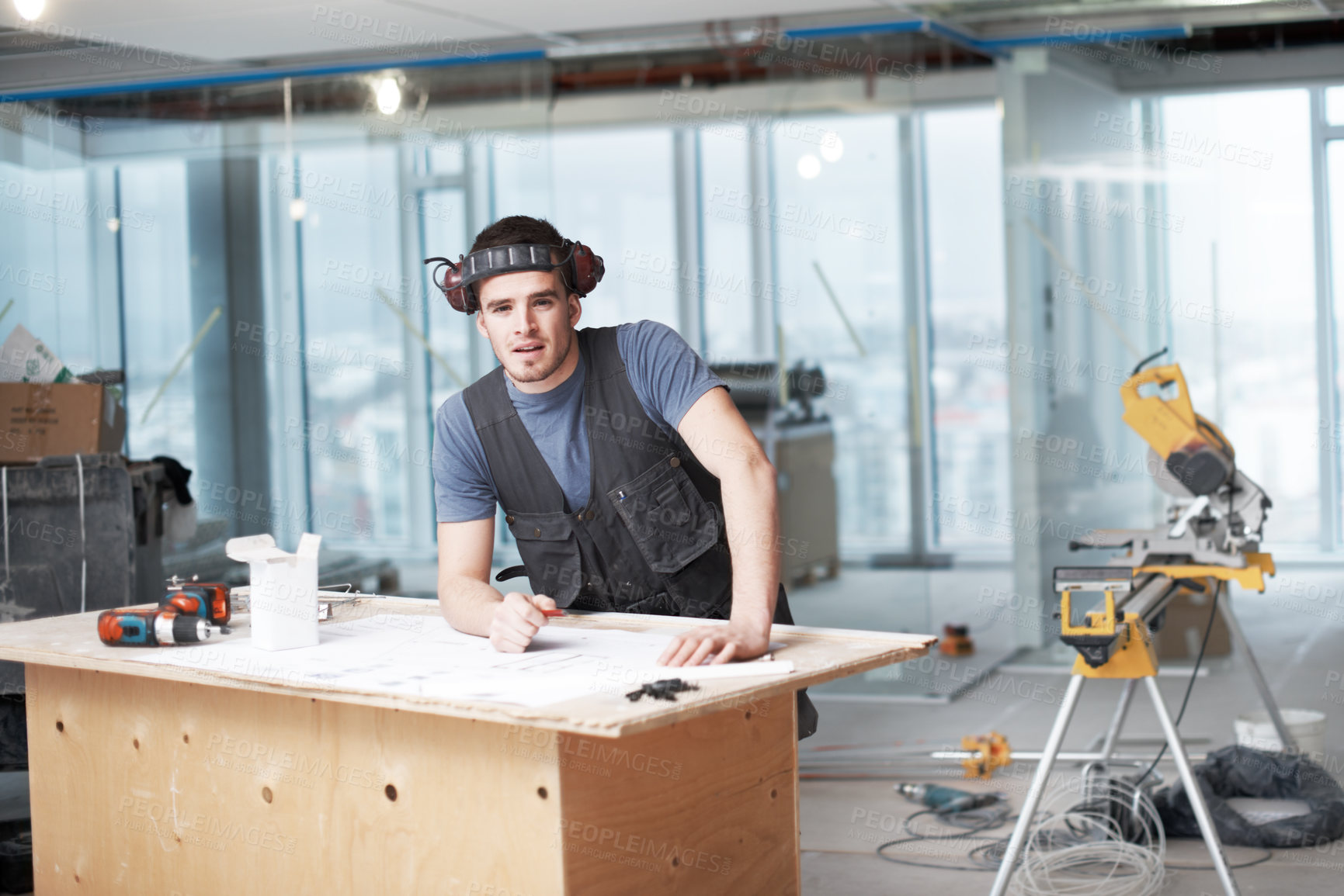 Buy stock photo Young architect working on his plans while at a construction site