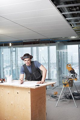 Buy stock photo Young architect working on his plans while at a construction site