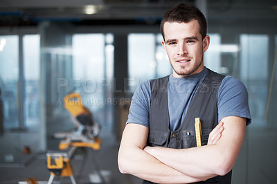 Buy stock photo Portrait of one confident young contractor standing with arms crossed working on industrial architecture project at construction site. Civil engineer builder installing and renovating property