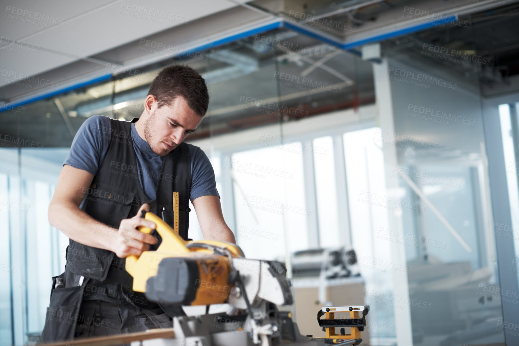 Buy stock photo Young contractor using a saw while on a construction site 