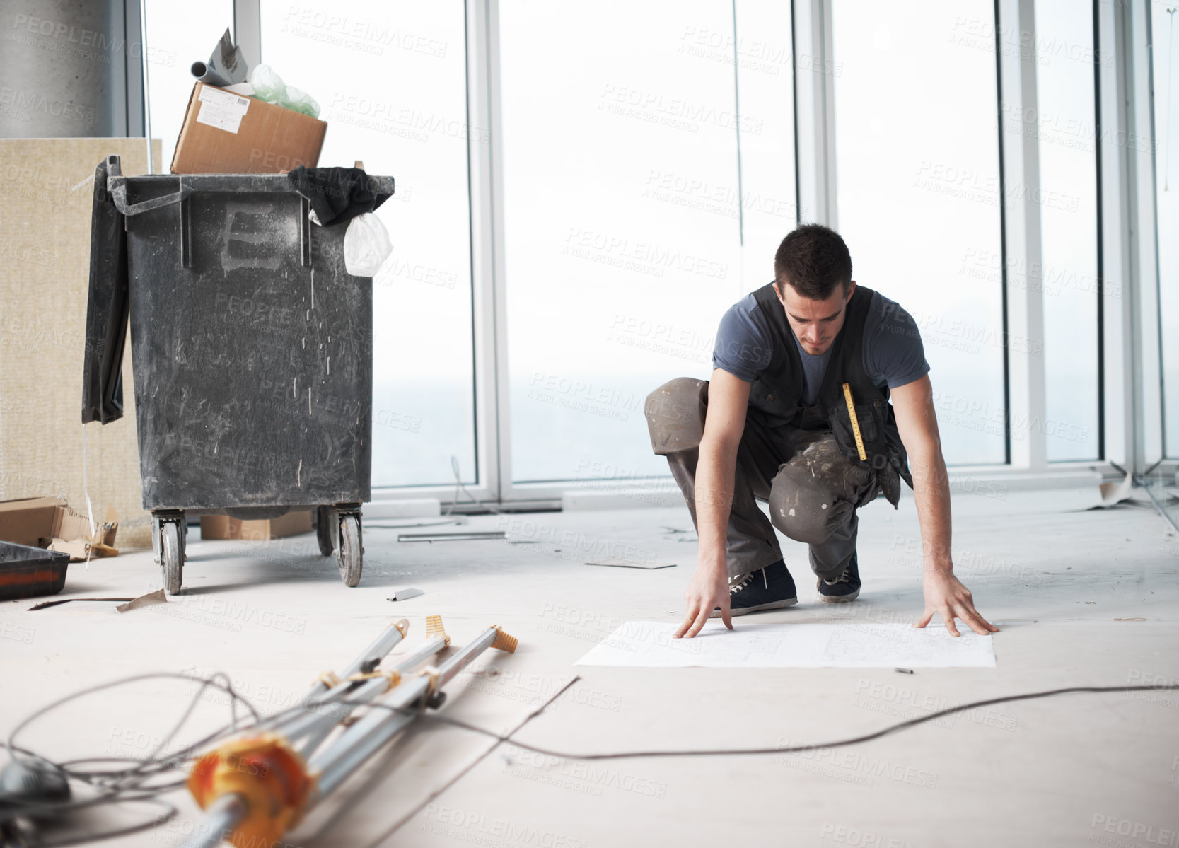 Buy stock photo Young contractor checking his plans on a construction site indoors