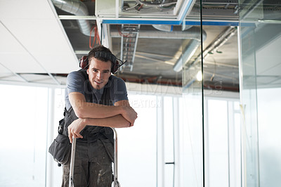 Buy stock photo Portrait of one happy young building contractor wearing noise cancelling headphone earmuffs climbing ladder for industrial architecture project at construction site. Engineer renovating property roof