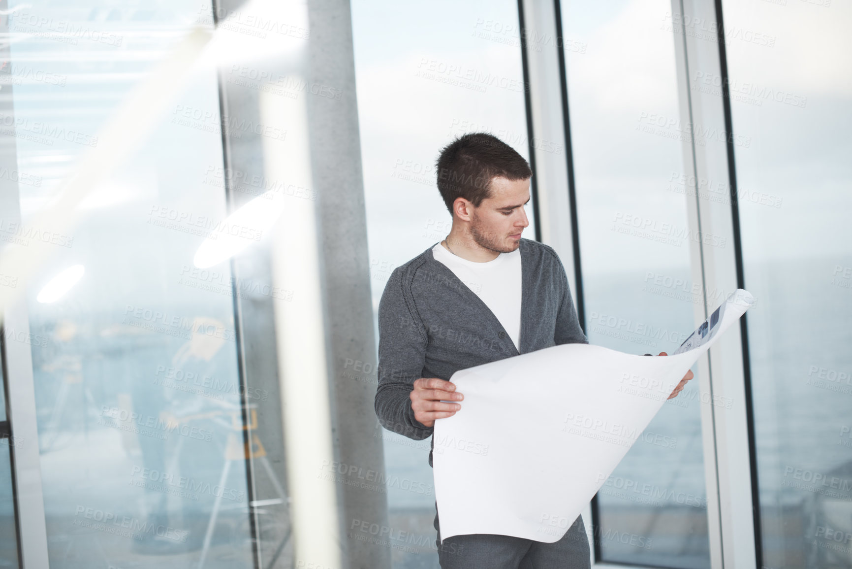 Buy stock photo Young architect checking his plans while standing in an empty room