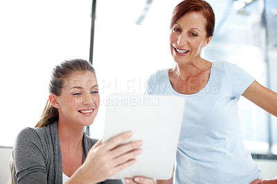 Buy stock photo A young businesswoman showing her colleague something on a digital tablet