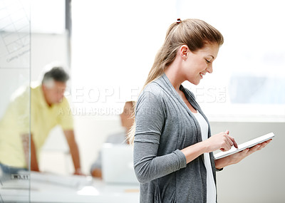 Buy stock photo Side view of a young female architect standing and using a digital tablet