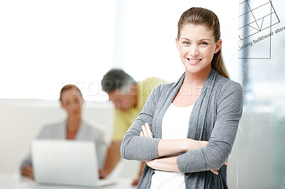 Buy stock photo A young architect standing confidently while her colleagues work in the background